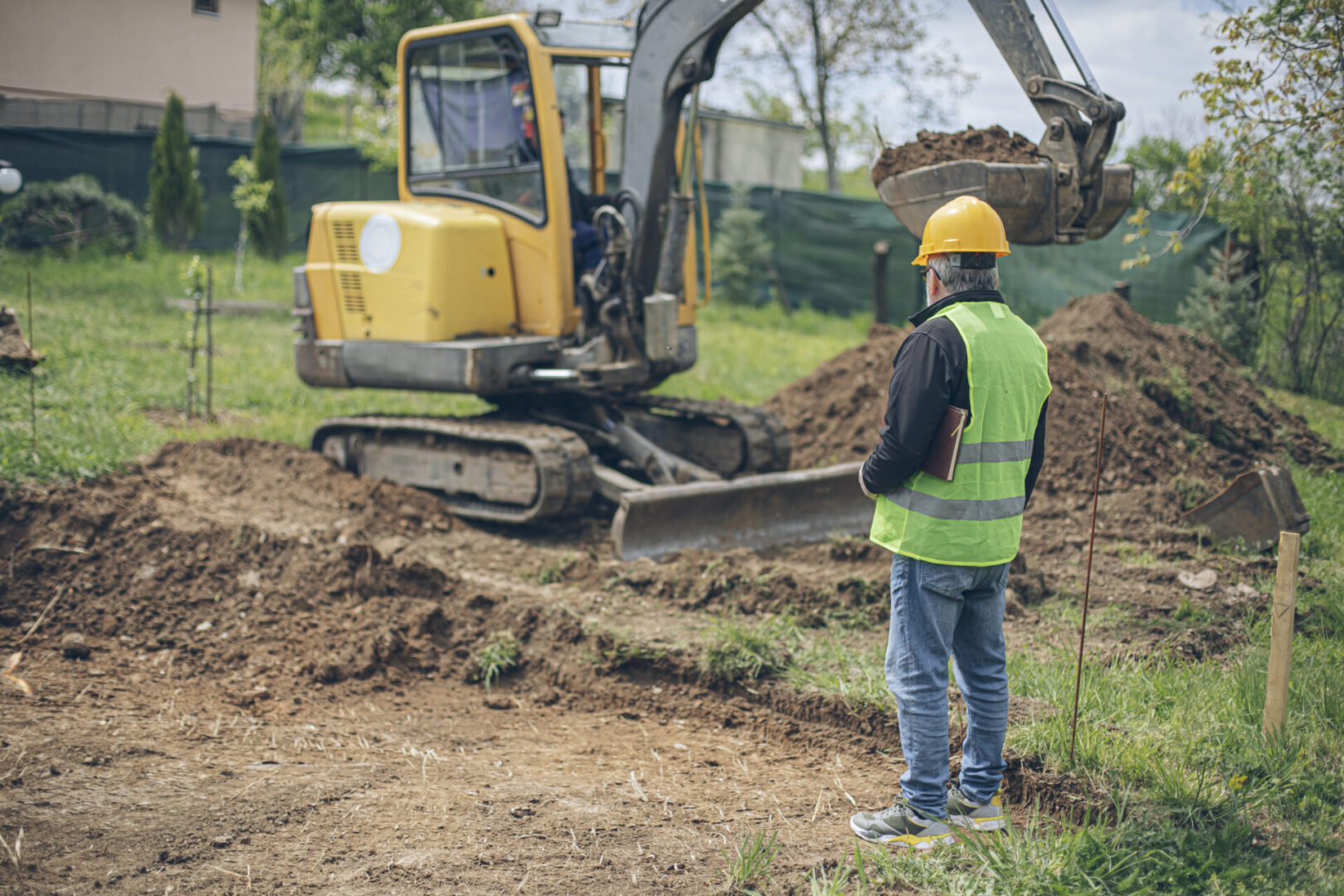 Civil engineer looking and coordinating an excavation process in homeowners backyard