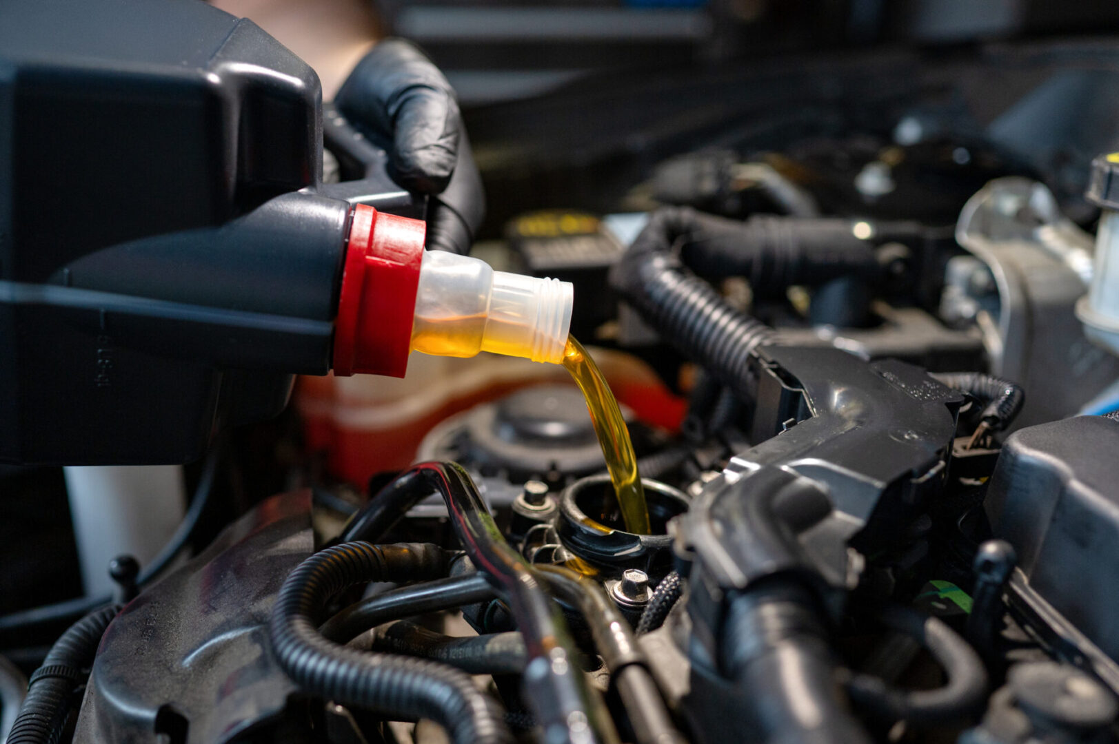 Close-up of engine oil being poured into a modern car engine during a maintenance procedure.